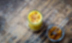 Ayurveda mit gelbem Getränk mit Kurkuma, Glas und Schüssel auf Holzuntergrund