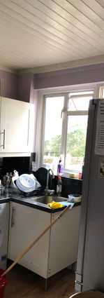 Cluttered galley kitchen before rear and side extensions.