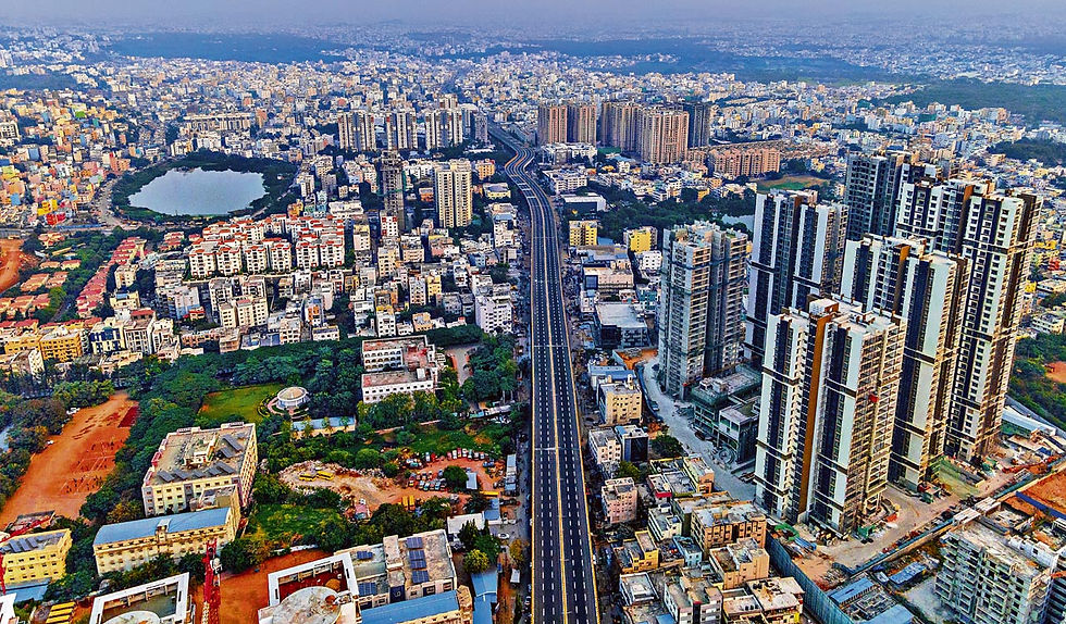 A vibrant aerial view of Hyderabad showcasing a bustling cityscape with modern skyscrapers, a vast expanse of residential buildings, and a prominent urban lake, highlighting the city's growth and dynamic skyline.
