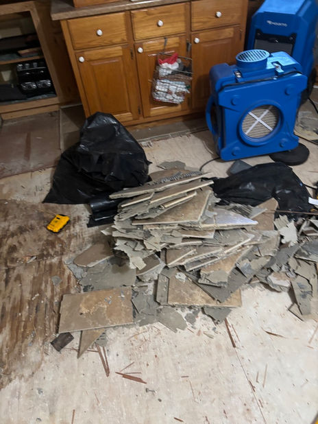 Broken floor tiles from water damage on wet floor, air mover.