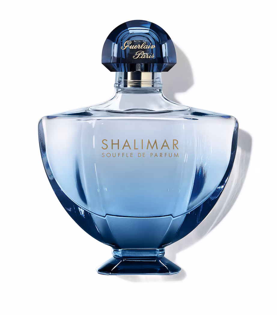 Frasco de Shalimar Souffle de Parfum em vidro com degradê azul, indo do transparente ao azul profundo na base. Design minimalista com tipografia dourada.