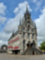 a large stone building with Gothic architecture and red and white shutters