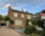 red brick home with driveway and front yard with blue sky