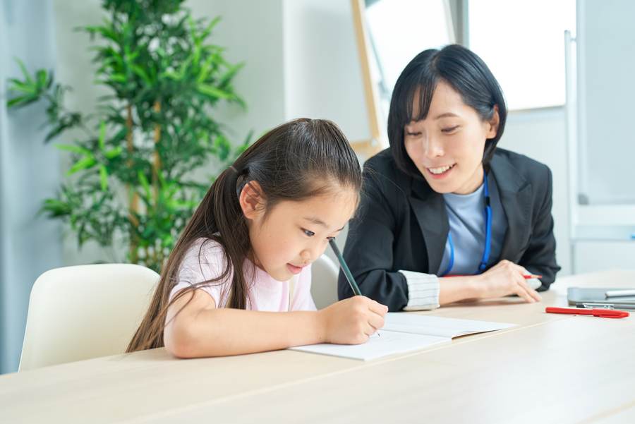 講師の解説を聞きながら勉強する小学生