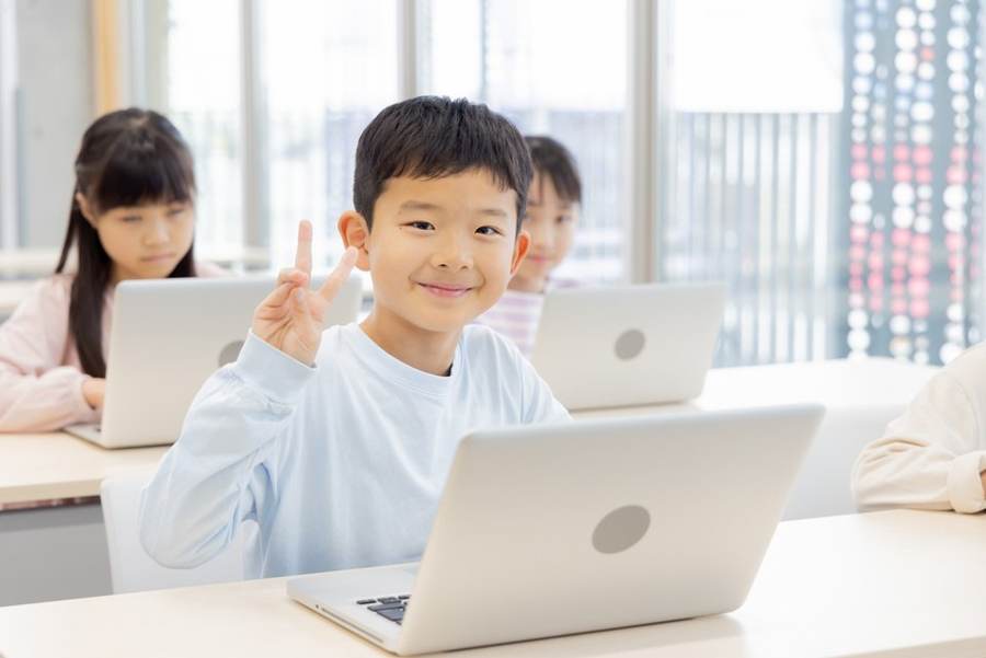 ノートパソコンでタイピングしながら英語を学ぶ小学生