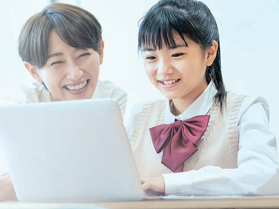 講師と一緒にパソコンで学ぶ生徒