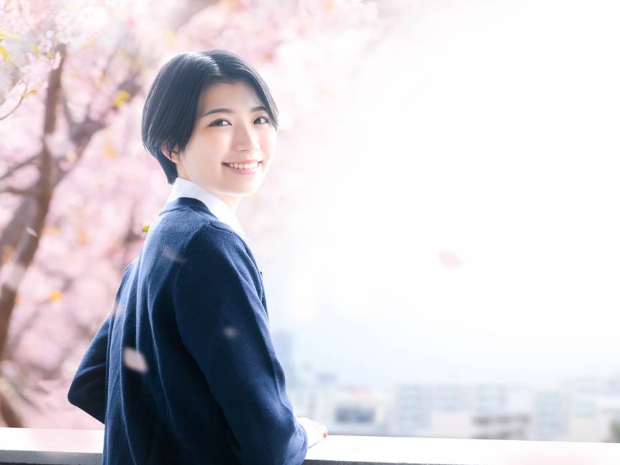 桜の前で笑顔の高校生
