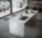 Modern kitchen with Sensa marble veins island countertop, stovetop, and sink. Gray stools, reflections on glossy floor. Patio with grill and chairs outside.