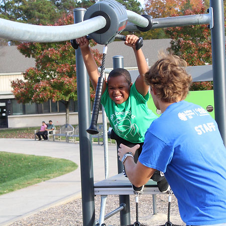 Staff member for Autism Society of Central Virginia playing with an autistic child at a playground