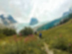 Two people hiking through a wildflower field towards the Bugaboo glacier in British Columbia