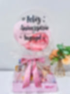 Cesta de café da manhã de aniversário com balão rosa personalizado e laço floral.