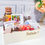 Miniatura: Cesta de café da manhã personalizada com biscoitos, suco, flores e balão, presente afetivo e elegante.