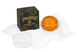 שרף Evah Pirazzi Gold בגוון זהוב, מונח על מטלית לבנה לצד אריזה שחורה עם כיתוב זהב.