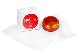 רוזין לכינור Pirastro Tonica בגוון כתום-אדמדם, מונח על מטלית לבנה לצד האריזה.