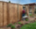 A Caucasian, middle-aged gay male carpenter builds a tall wooden fence..jpg