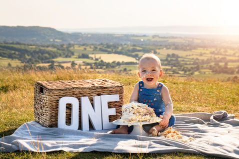 Baby celebrating their first birthday with a messy cake smash session at Rado Photo Studio.