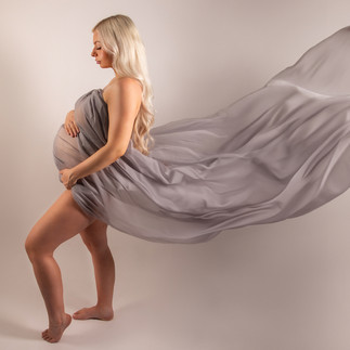 Maternity photographer guiding client into a flattering pose in Gloucester studio