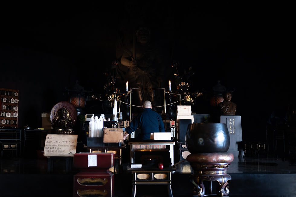 寺院の本堂、大仏、僧侶を捉えた奥行きのある構図。その場の静謐な空気感と湿度まで描き出された描写