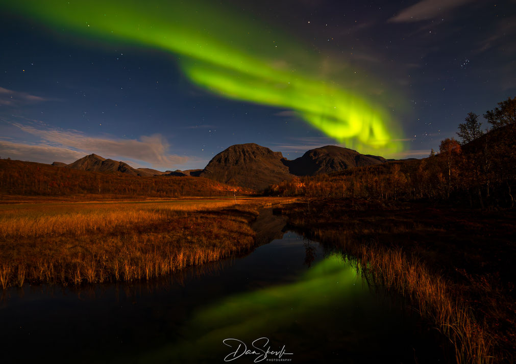 Nordlys over fjell og vann. Grønt lys i nattehimmelen. Dan Skovli Photography.
