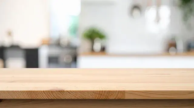 Wooden countertop in a bright kitchen setting. Background features blurred plants and kitchen utensils, creating a clean, fresh ambiance.