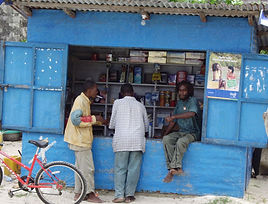 In an unreached people group, three men stand outside a rural storefront.