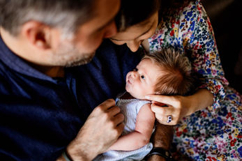 Parents admirant leur bébé nouveau-né avec tendresse, séance photo naissance domicile à Vincennes