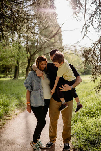 Futurs parents et leur ainé dans les bras, séance photo grossesse dans le bois de Vincennes