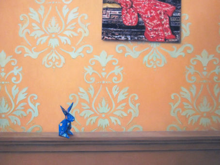 Een ansichtkaart van het schilderij De rode kimono van Breitner op een muur met behang.