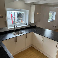 A small U-shaped kitchen with a black granite countertop and white cabinets