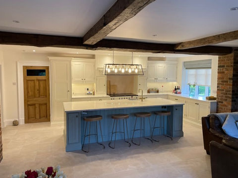A modern kitchen with blue cabinets and exposed wooden beams