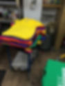 A stack of colourful T-shirts on a bench