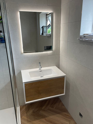 A washbasin and a mirror with lighting installed
