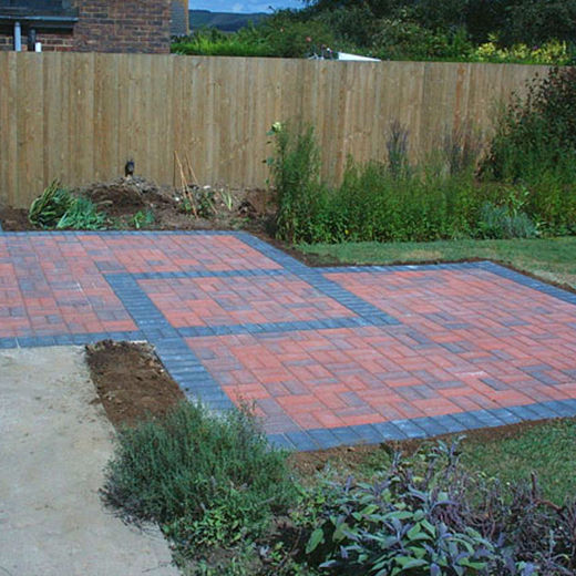 A brick patio surrounded by a wooden fence