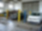 Two cars are parked in a garage with yellow and blue posts