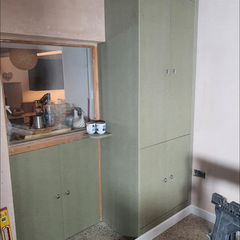 An olive green floor-to-ceiling cabinet in the kitchen