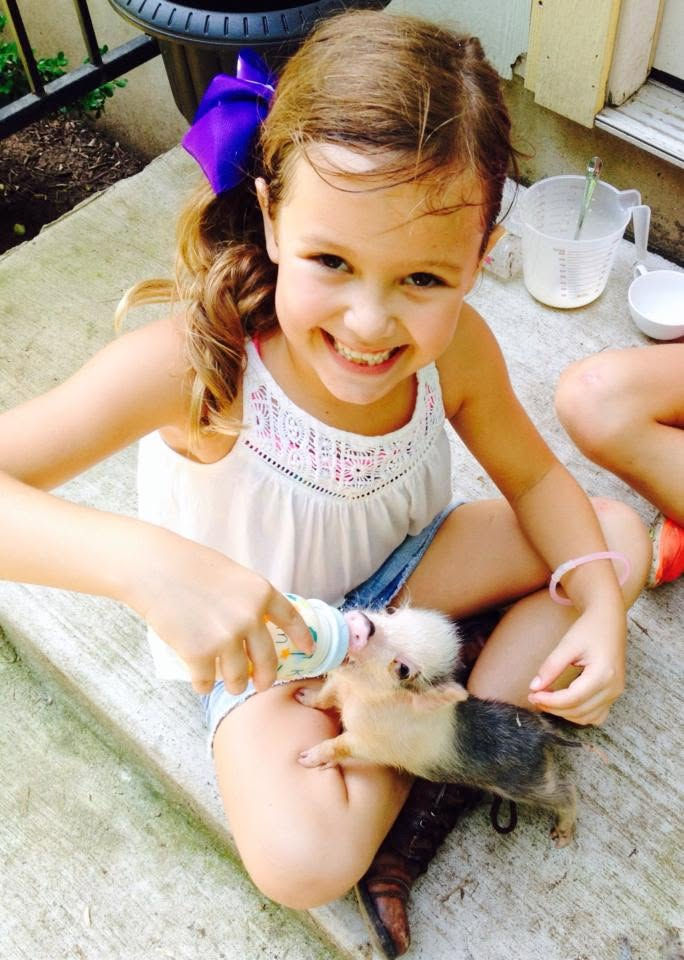 Young girl bottle-feeding a piglet at Farm Summer Camp