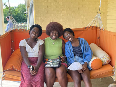 three young Black people sit together smiling on a swing