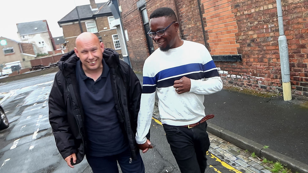Two men walking and holding hands on a street smiling together