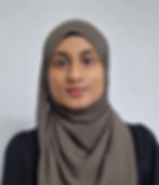 Young woman wearing a hijab smiles at the camera, neutral background.