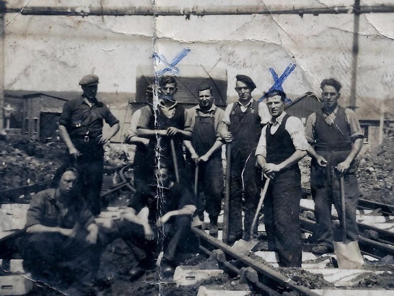 Seven workers with tools at a historical worksite