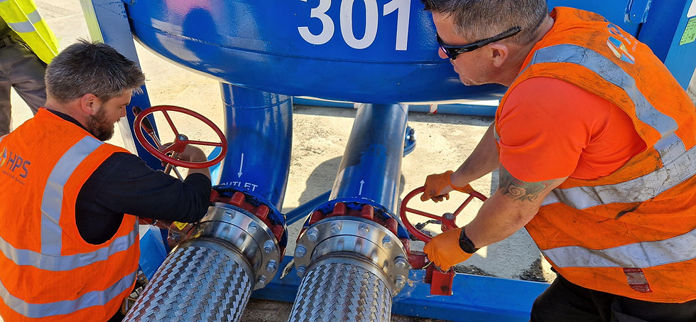 Two workers in safety vests adjusting valves on blue industrial pipes.