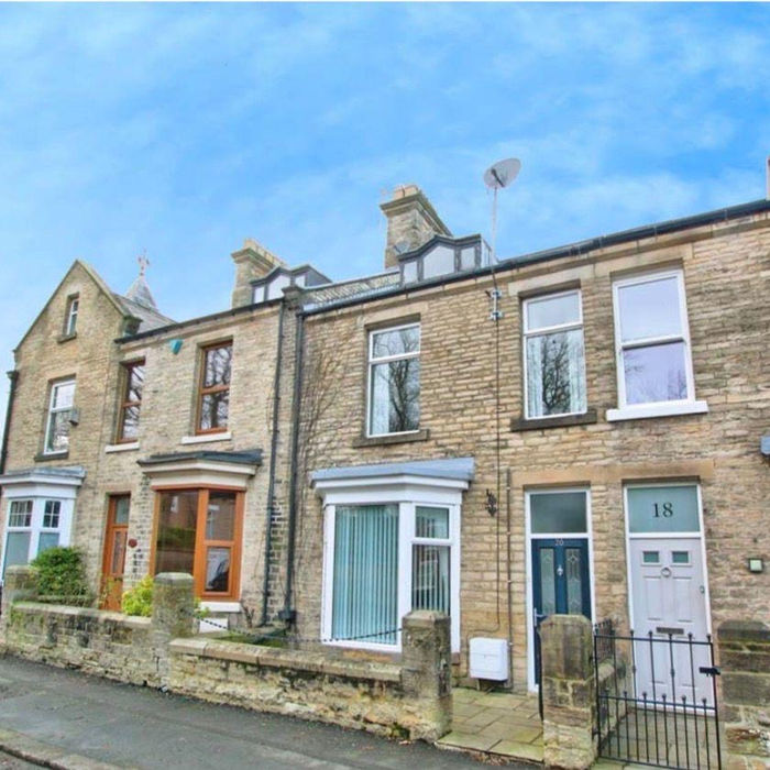 Terraced stone houses with bay windows, numbers 18, 19, under blue sky.
