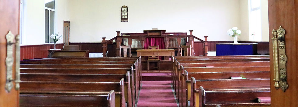 Open doors to inside of Treharris Evangelical church with pews and pulpit.