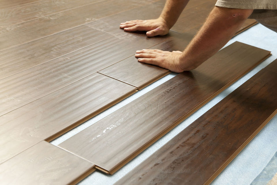 close up of a contractor installing pre-finished hardwood flooring
