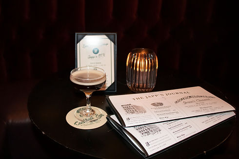 An espresso martini on a table next to the bar's menu and promotional tents