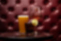 A pint of beer, a glass of white wine, and a brown-colored cocktail with a lime wheel
