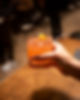 A hand holding an orange cocktail with a lemon garnish