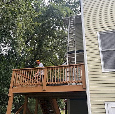 Professional cleaning leaves and debris from a home gutter in Apex, NC