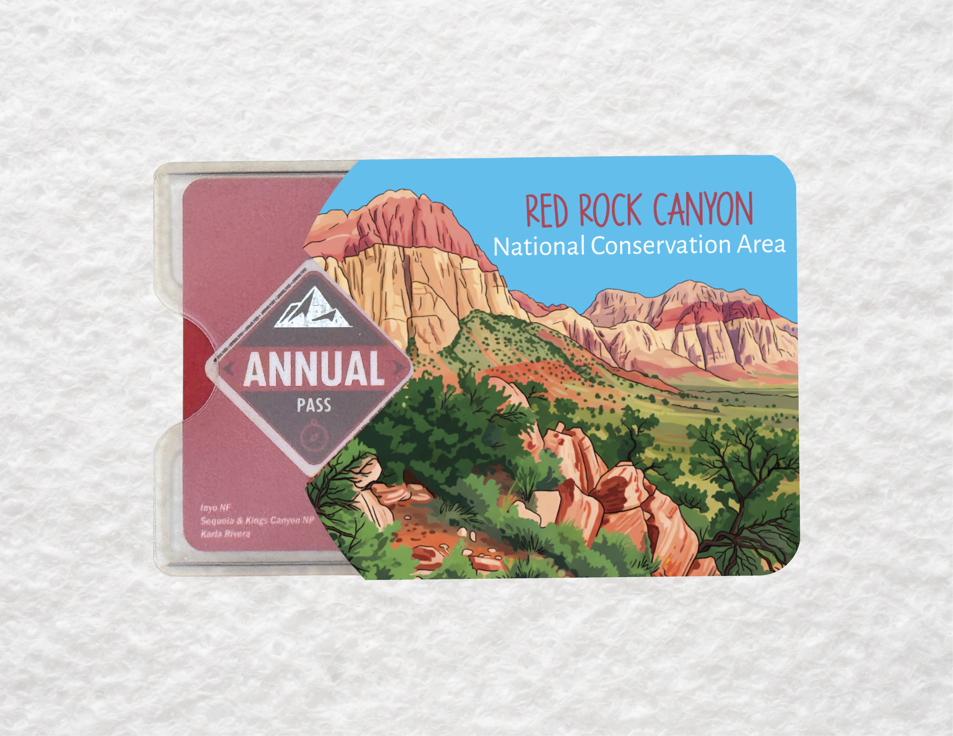 A plastic sleeve holding a National Parks pass. The sleeve has a design of Red Rock Canyon National Conservation Area on it.