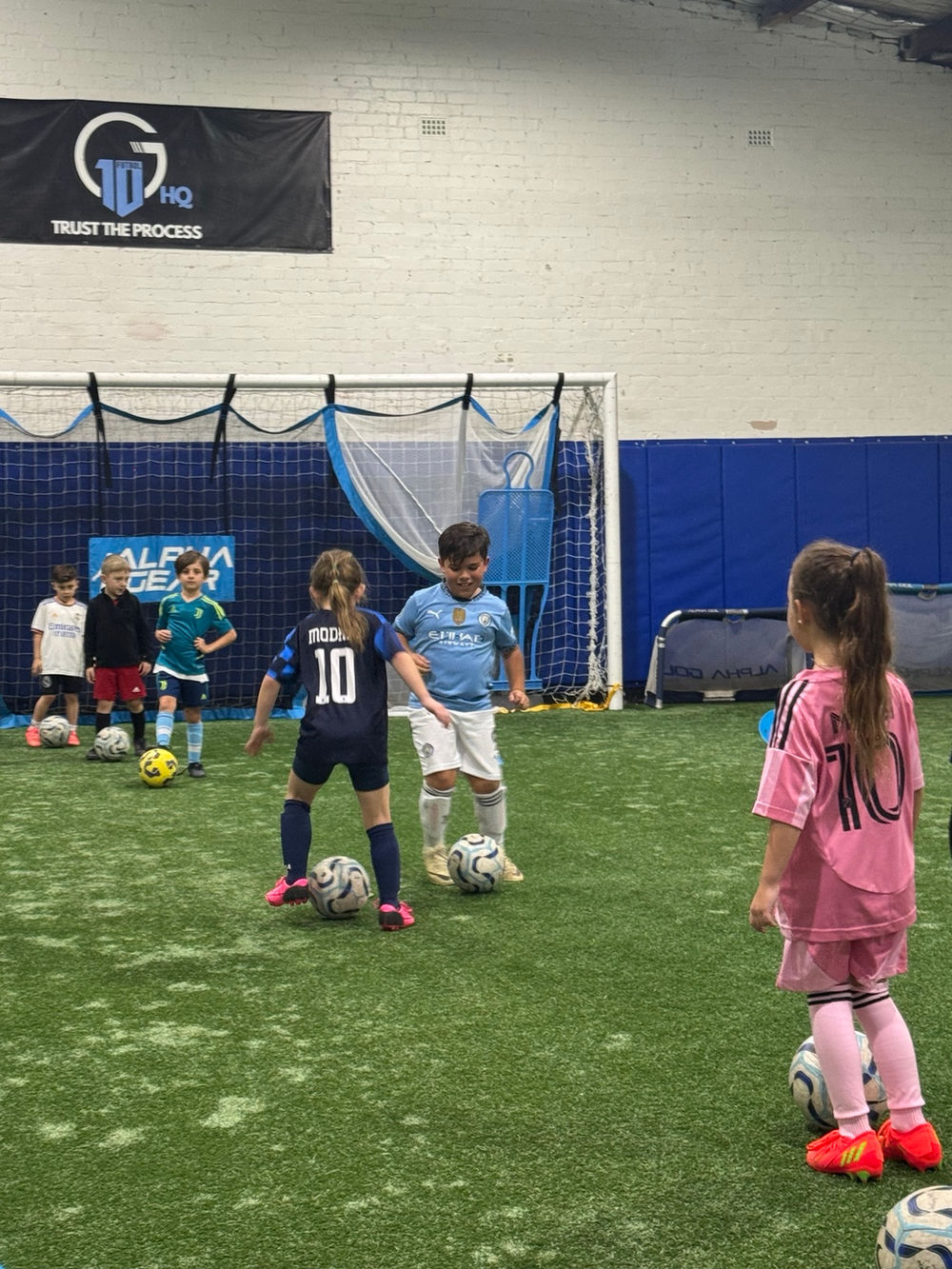 Boys and girls training together at G10 HQ, with a girl and a boy competing for the ball